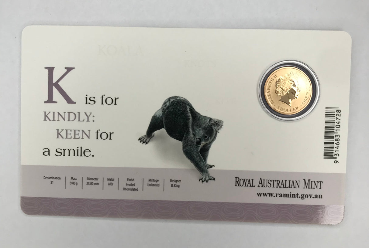2015 $1 Uncirculated Carded Coin. ‘K’ is for Kindly. Keen For a Smile.
